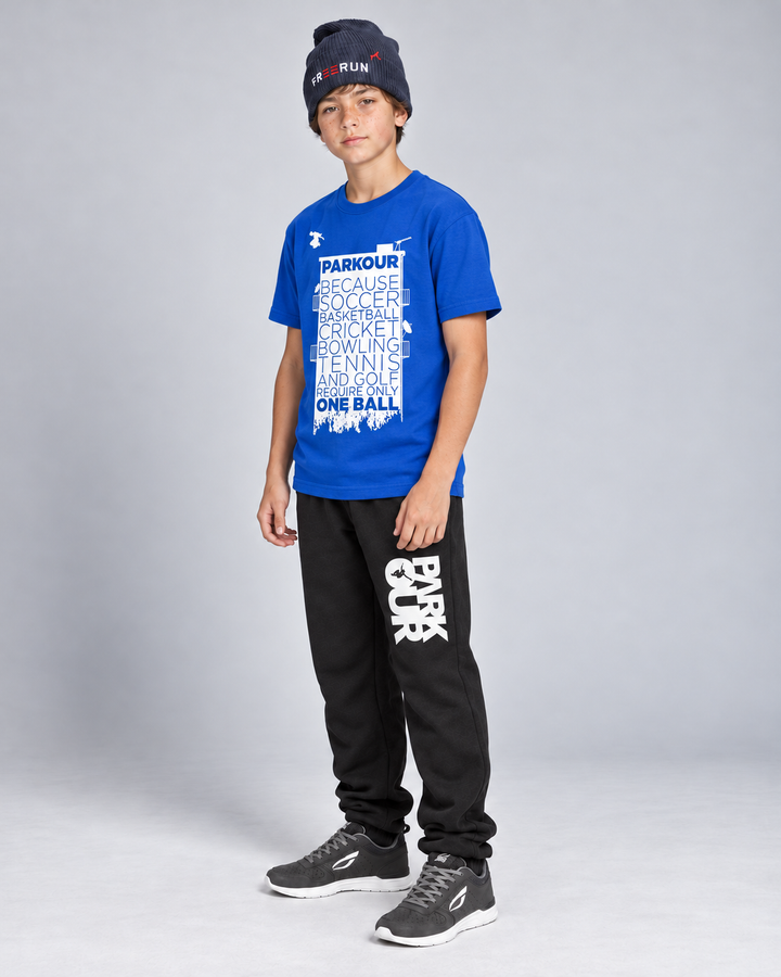 Blå Parkour Takes BALLS T-shirt med sorte/hvide bukser og navy FREERUN-hue – fra siden.