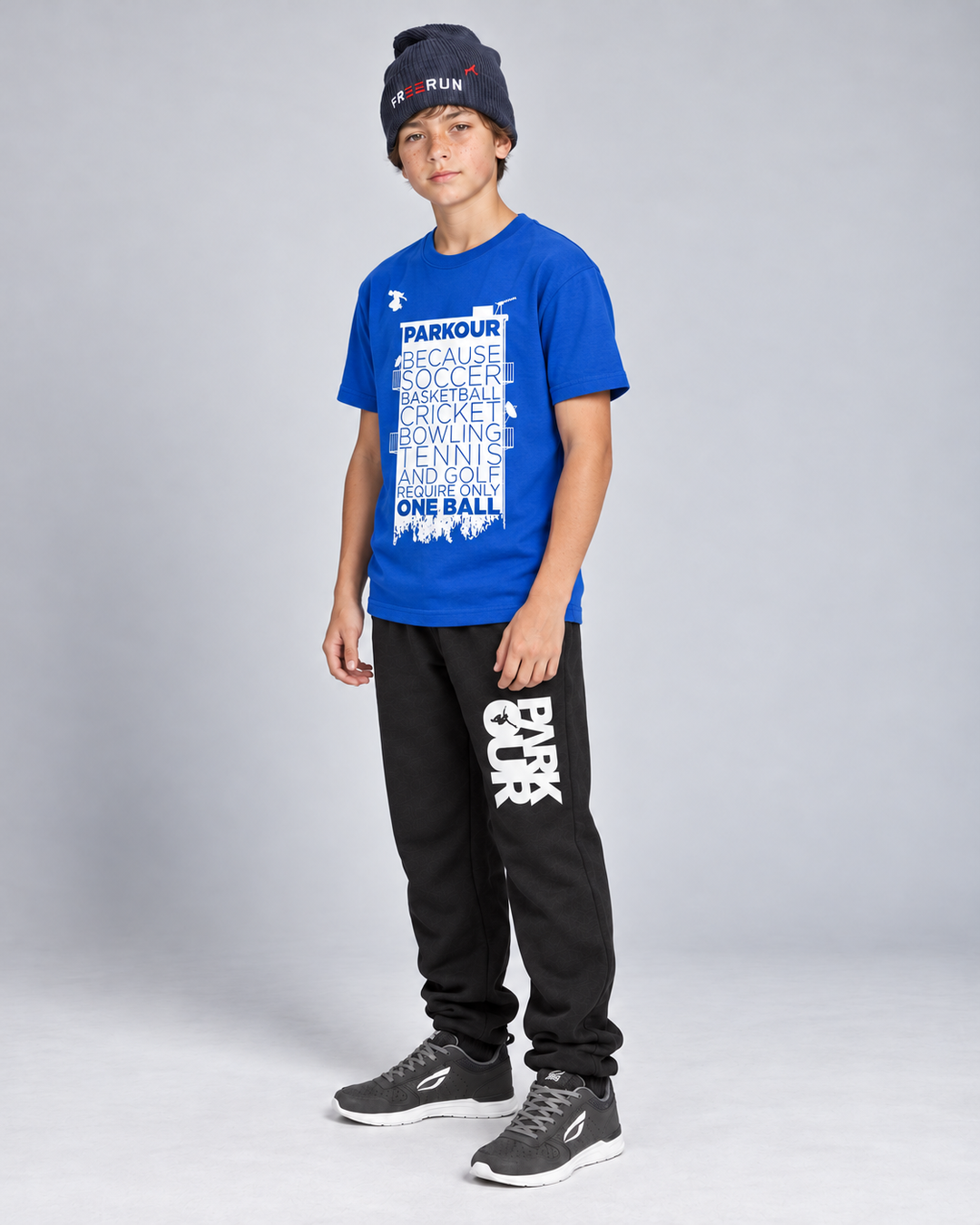 Blå Parkour Takes BALLS T-shirt med sorte/hvide bukser og navy FREERUN-hue – fra siden. Sko købes separat.