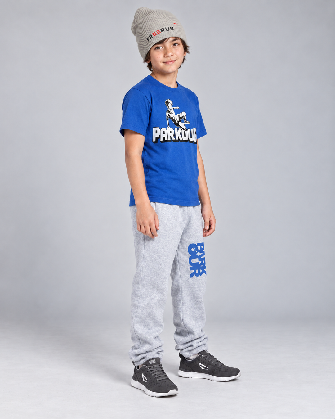 Blå Traceur T-shirt og grå/blå bukser med grå FREERUN-hue – fra siden. Sko købes separat.