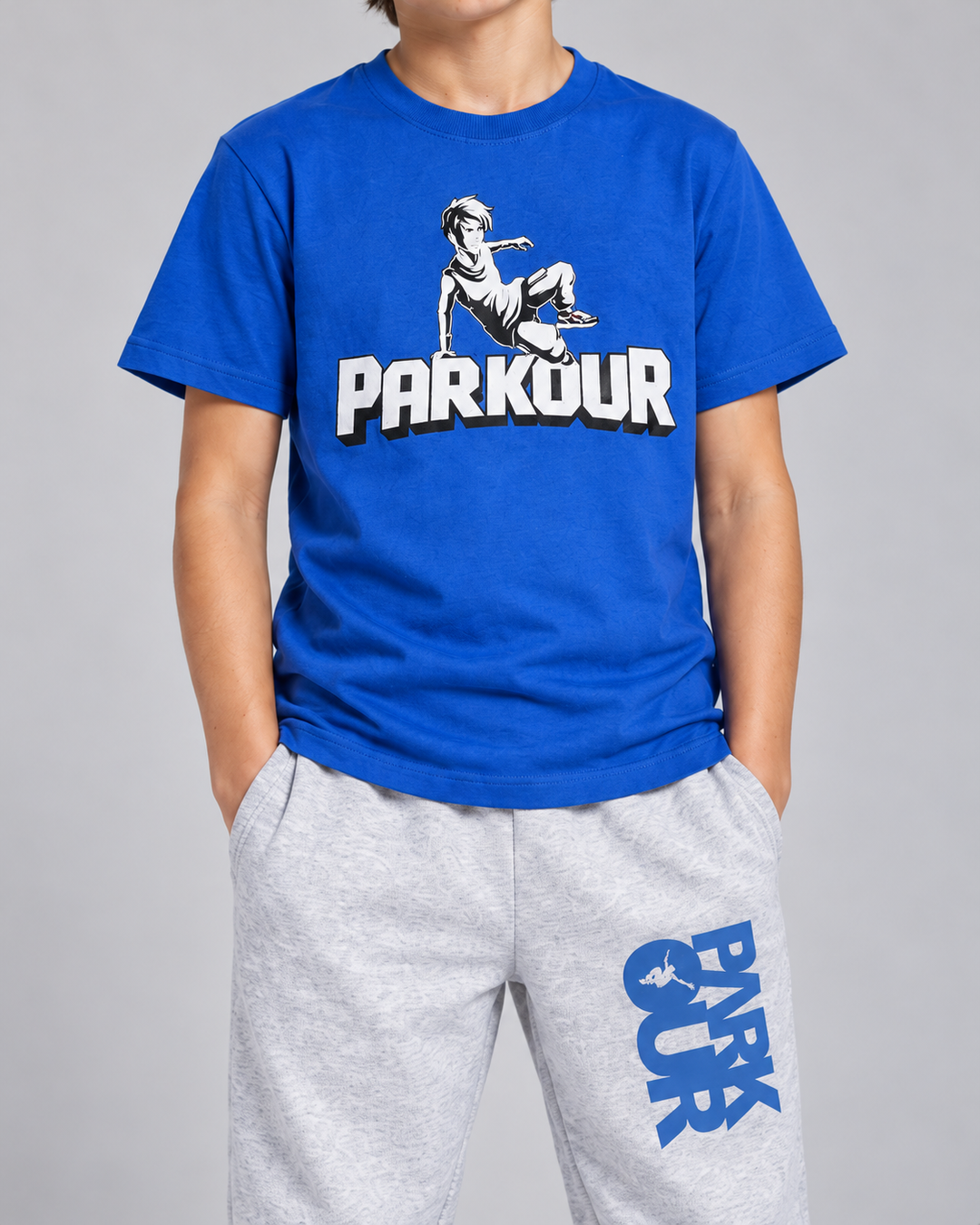 Blå Traceur T-shirt og grå/blå bukser med grå FREERUN-hue – detalje af tryk og materiale.