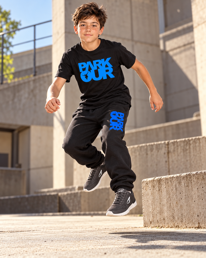 T-shirt og bukser fra den sort/blå startpakke – i brug under parkour. Hue og eventuel hoodie ses på pakkens oversigtsfoto. Sko købes separat.