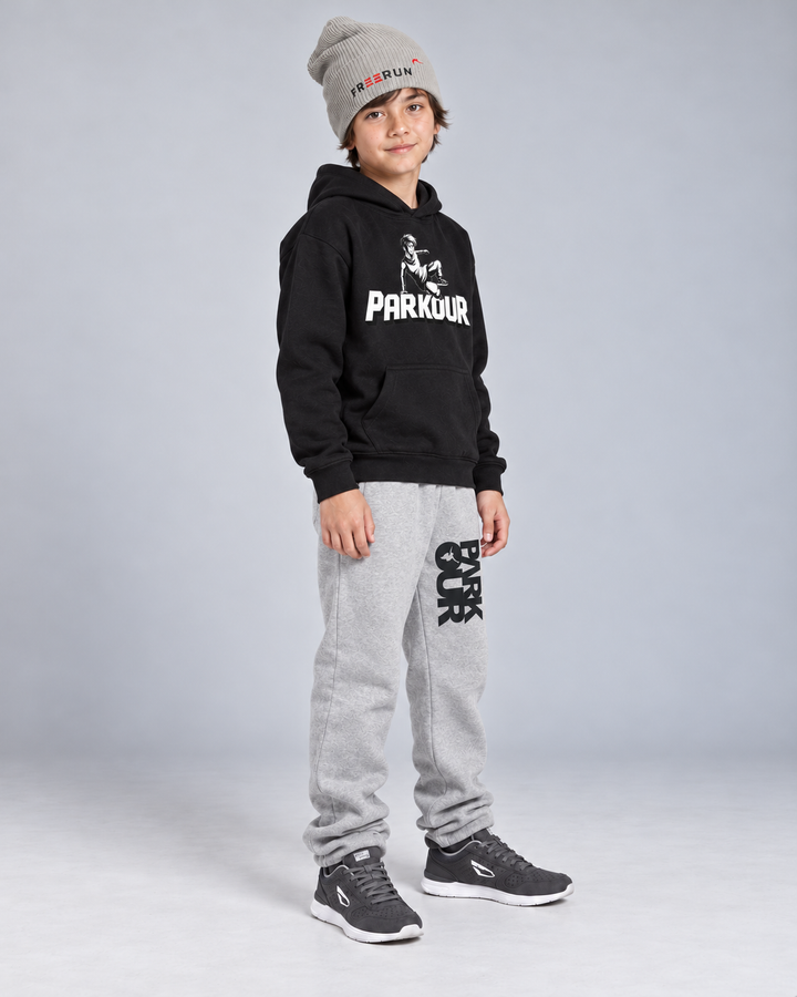 Sort Traceur-hoodie, grå/sorte bukser og grå FREERUN-hue – fra siden.