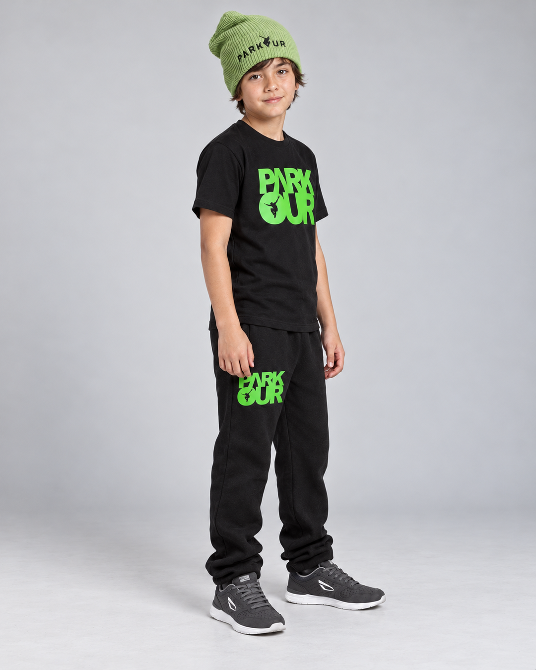 Samme dreng i sort/grøn Parkour T-shirt og bukser set fra siden