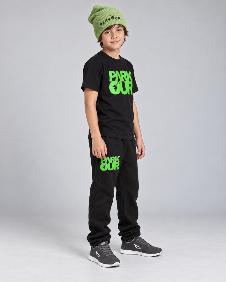 Samme dreng i sort/grøn Parkour T-shirt og bukser set fra siden