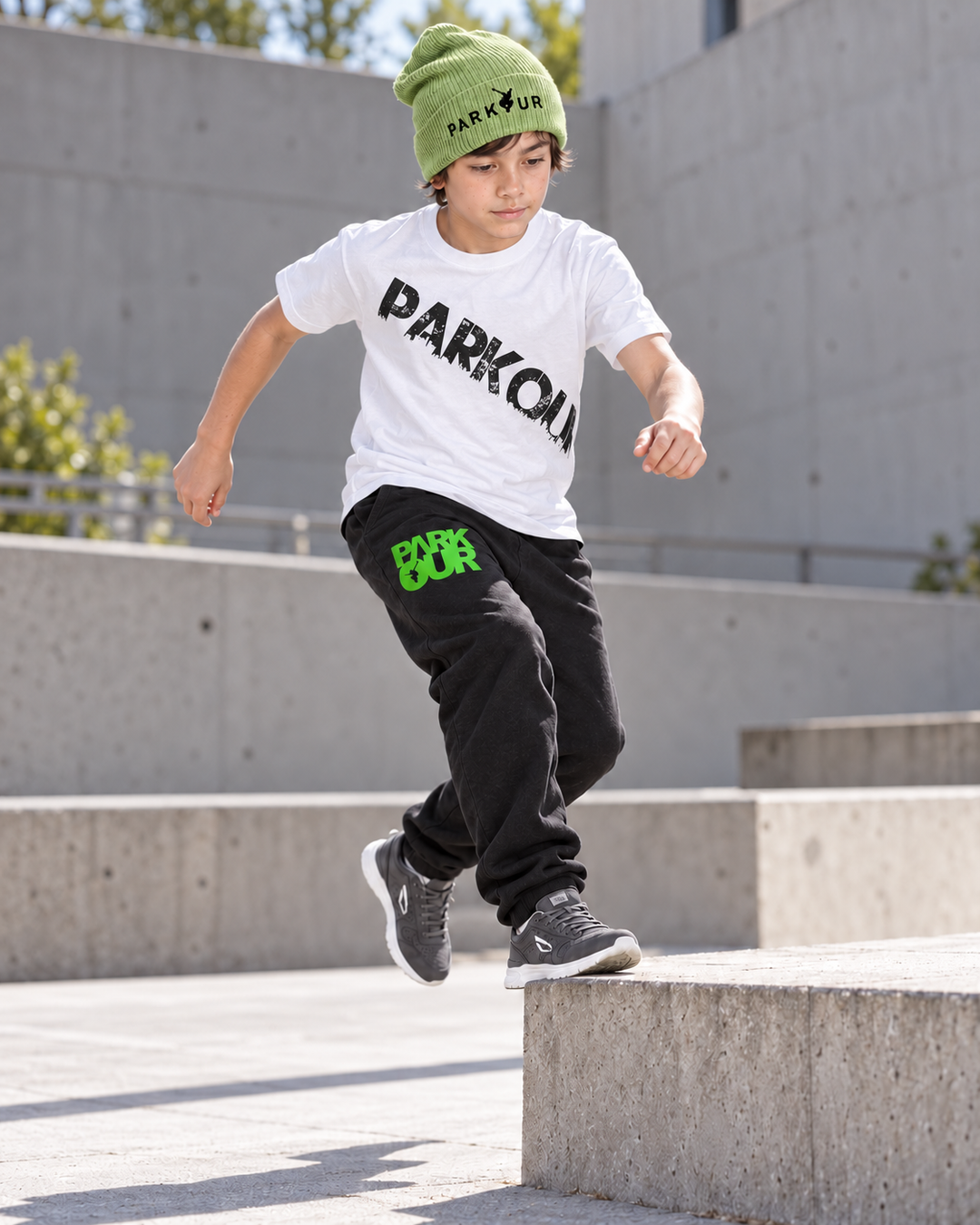 Hvid Urban Parkour T-shirt med sort diagonalt tryk, sorte/grønne bukser og grøn hue – i brug.