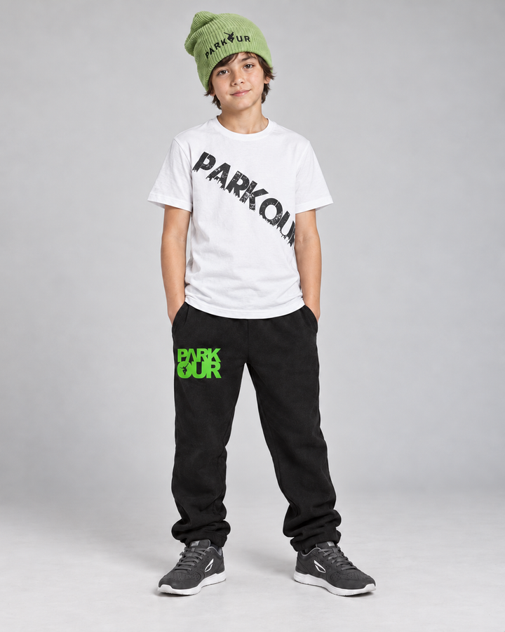 Hvid Urban Parkour T-shirt med sort diagonalt tryk, sorte/grønne bukser og grøn hue – forfra.