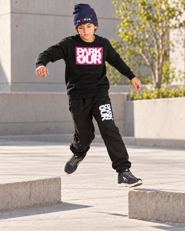 Sort/pink/hvid Parkour-sweatshirt – i brug til parkour. Øvrig styling købes separat.