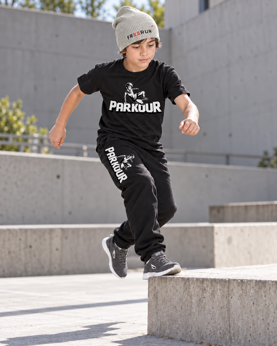 Traceur T-shirt og sorte Traceur-bukser med grå FREERUN-hue – under parkourtræning.