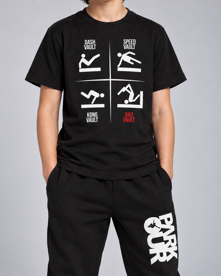 Sort VAULTS T-shirt med sorte/hvide bukser og grå FREERUN-hue – detalje af tryk og materiale.