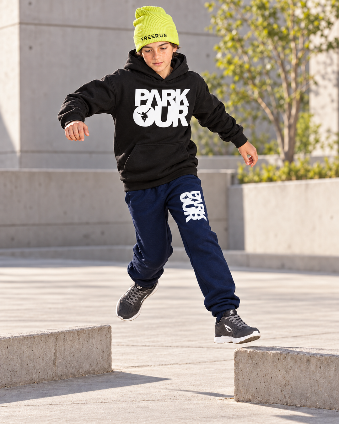 Sort/hvid Parkour-hoodie, navy box-bukser og gul FREERUN-hue – under parkourtræning.